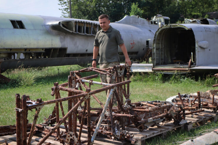 Member of the Armed Forces of Ukraine walking past the rusty remains of a Hawker Hurricane's fuselage
