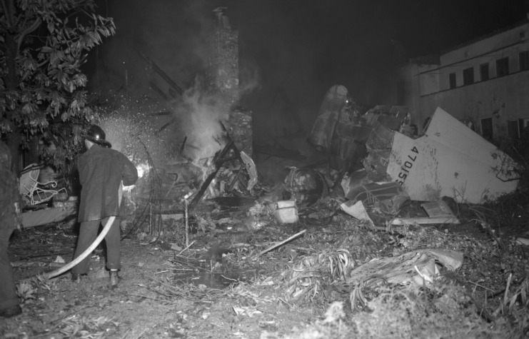 Fire crews putting out a fire among the debris of a Hughes XF-11