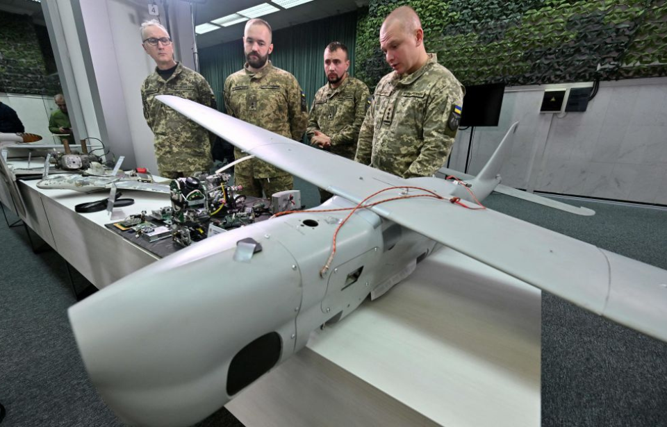 Ukrainian military officials standing with Russian drones