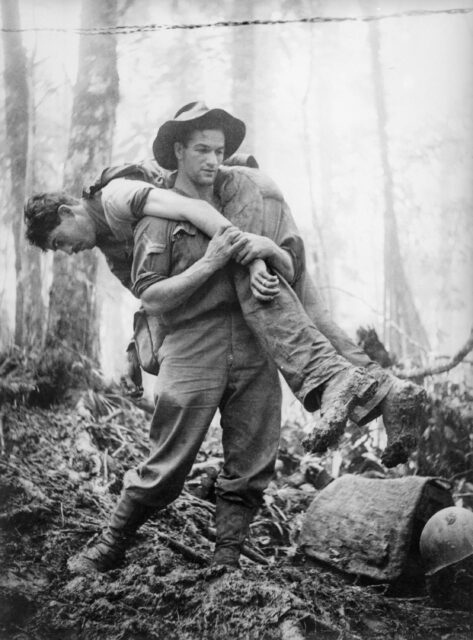 Leslie "Bull" Allen carrying an injured American soldier through the jungle