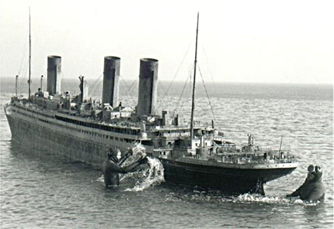 Two frogmen standing around a replica of the RMS Titanic, in the middle of the water