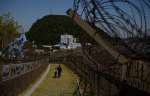 Man and child walking along the barbed wire fence of the Demilitarized Zone (DMZ) between North and South Korea