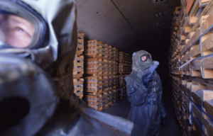 Two workers walking through a room stocked with M55 rockets