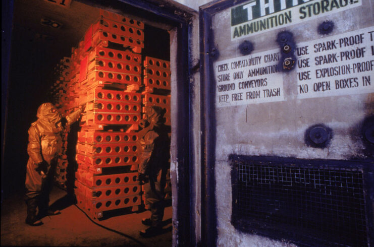 Two workers examining rows of M55 rockets in a room