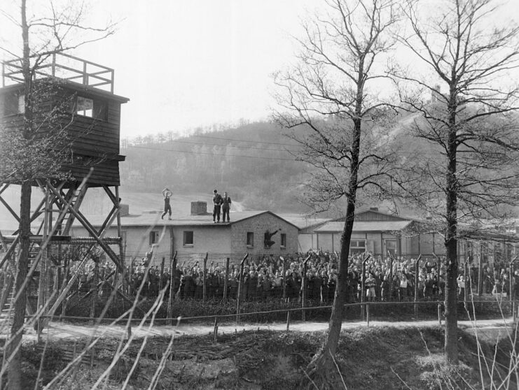 Allied prisoners of war (POWs) standing behind barbed wire