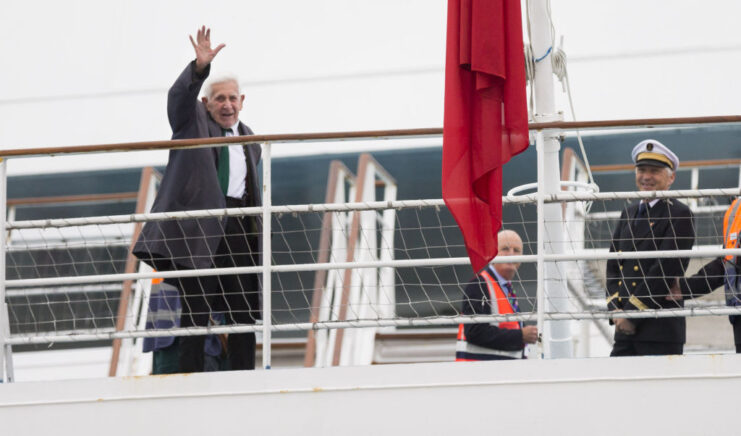 Bernard Jordan waving from the deck of a ferry while crewmen stand nearby