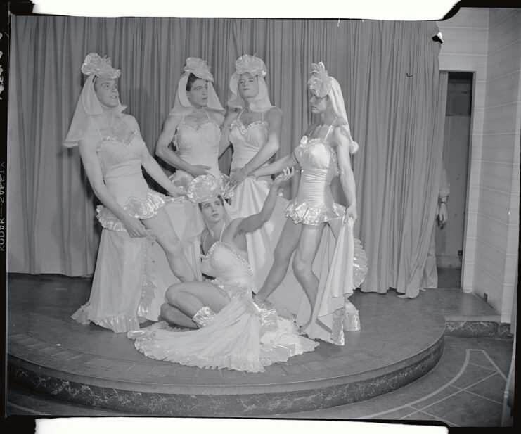 Joe Johnson, Robert Sidney, Phil Wernick, Lee Berg and Nelson Barclift wearing wedding dresses while standing on stage