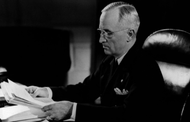 Harry Truman sitting at his desk in the Oval Office