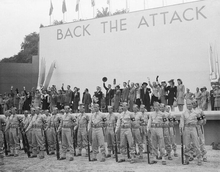 Celebrities standing on stage while US military personnel stand before them in uniform