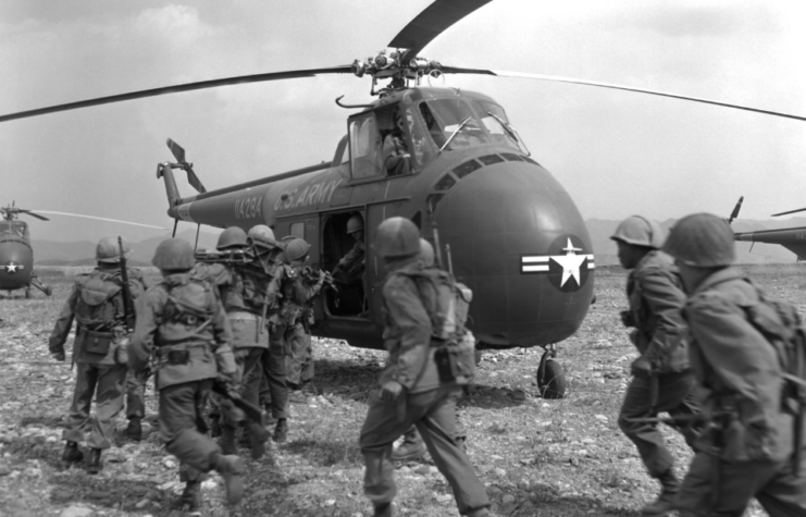 US infantrymen running toward helicopters in the field