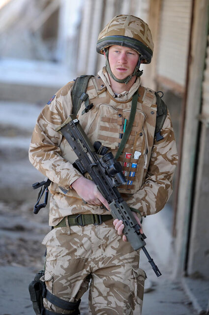 Prince Harry walking with a weapon while in uniform