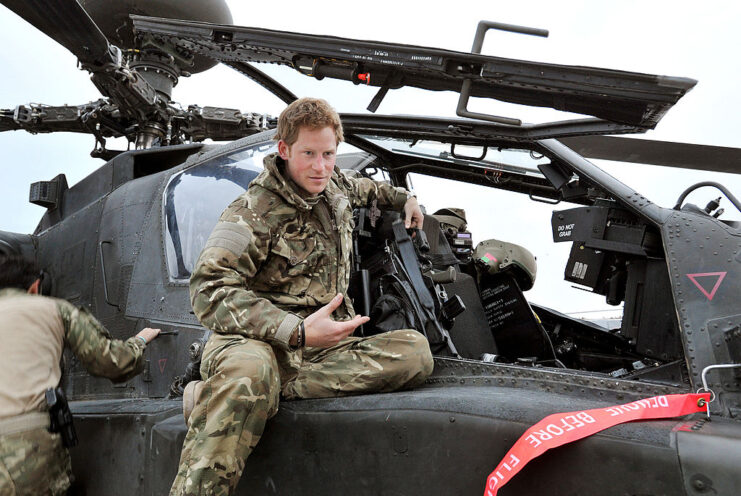 Prince Harry sitting on the exterior of an Apache helicopter