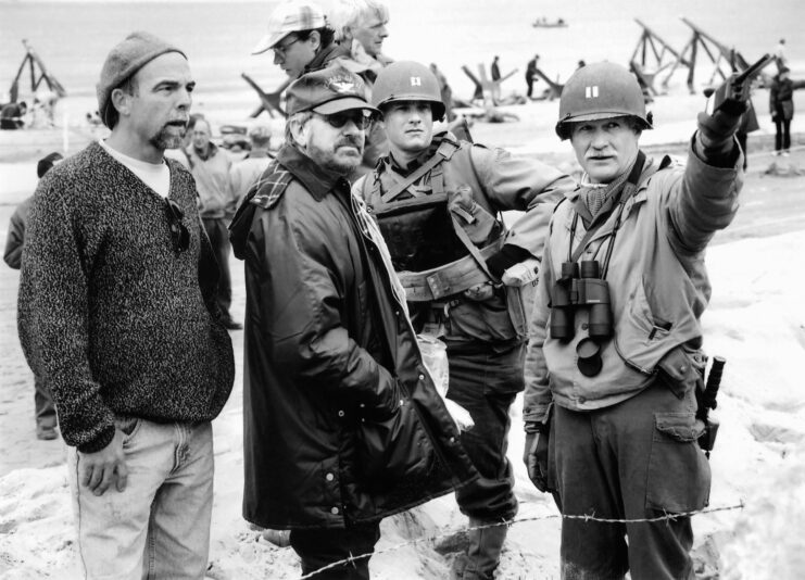 Dale Dye standing with Steven Spielberg, Tom Hanks and an unidentified crew member on the set of 'Saving Private Ryan'