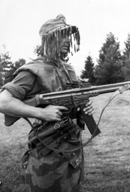 German infantryman holding an StG 44 while wearing a ghillie cap