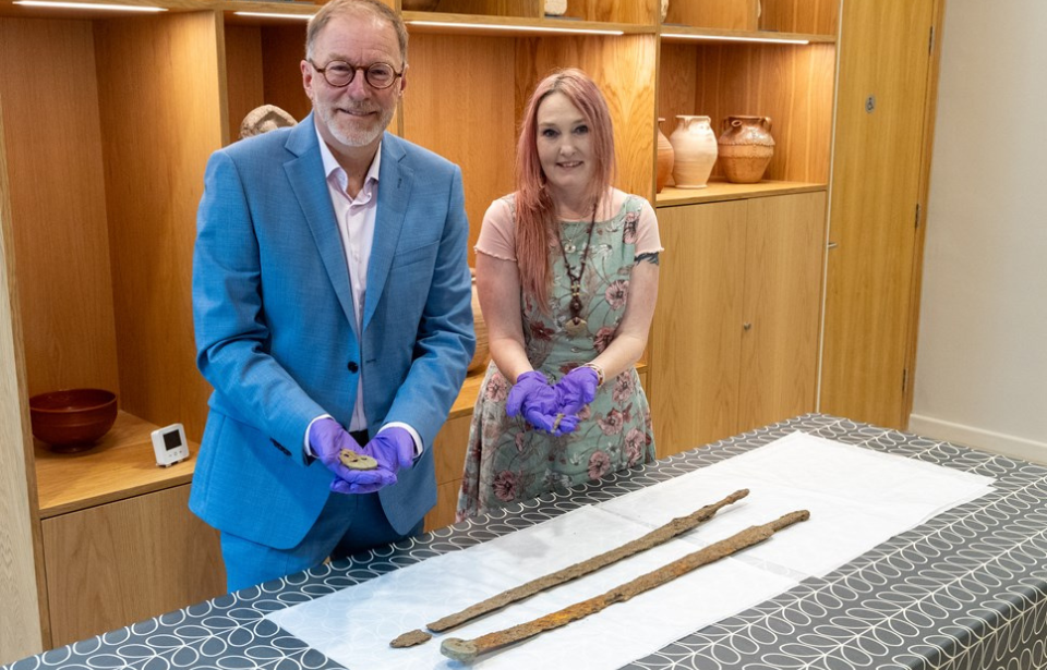 Paul Hodgkinson and Emma Stuart standing with two ancient Roman swords