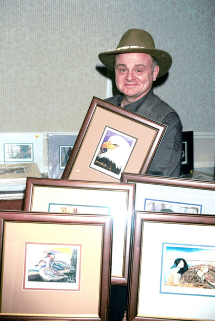 Gary Burghoff standing among framed paintings