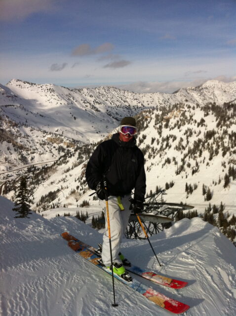 Glen Doherty wearing skis and winter clothing atop a mountain