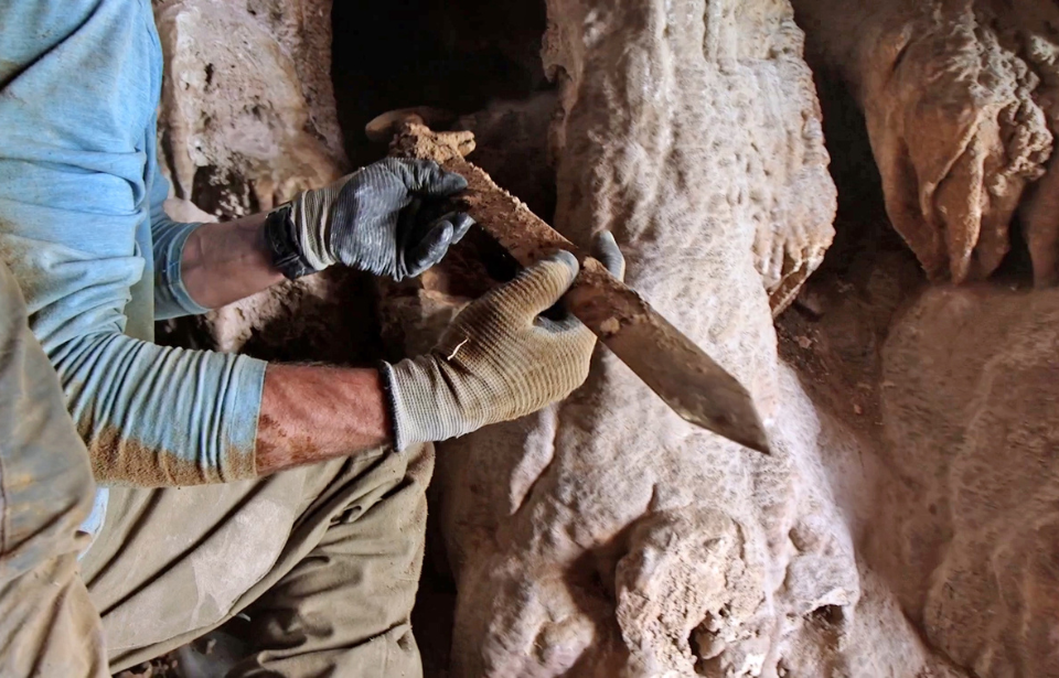 Archaeologist holding a Roman-era sword found in a cave