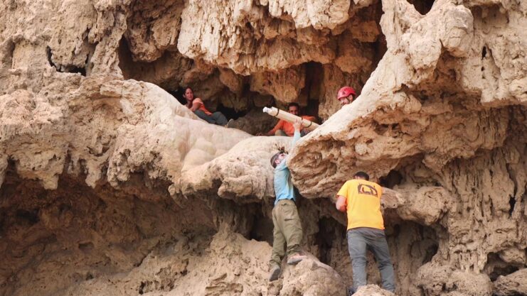 Team of archaeologists removing a Roman-era sword from a cave
