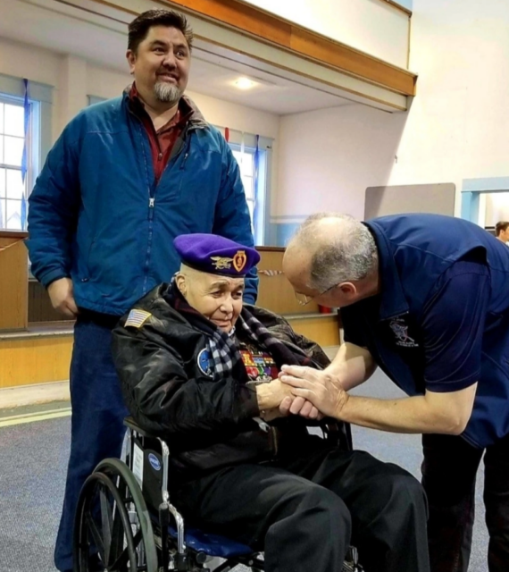 Solomon Atkinson being greeted by a representative of the Veterans Advocacy Organization, while his son-in-law, Franklin Hayward, stands behind him