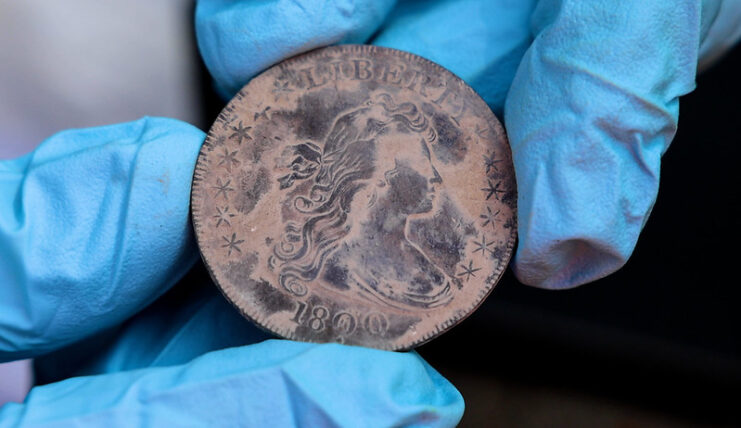 Gloved hands holding a silver coin