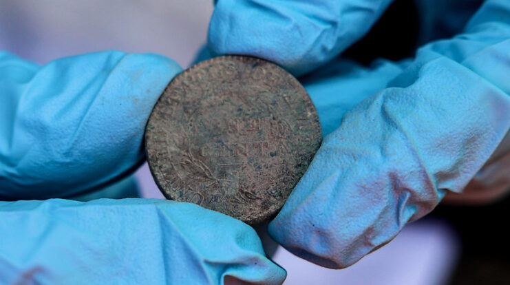 Gloved hands holding a silver coin