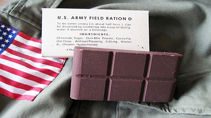 Slab of Field Ration D placed atop a military uniform with an American flag and an index card
