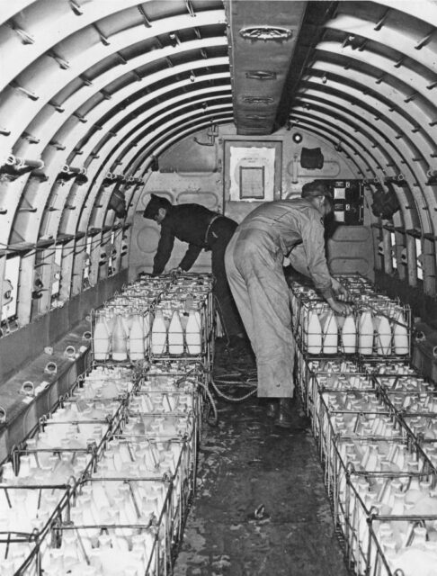 Two airmen loading milk into the cargo-hold of a Douglas C-47 Skytrain