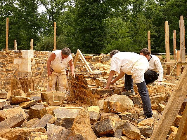 Three construction workers standing among bricks and pieces of stone