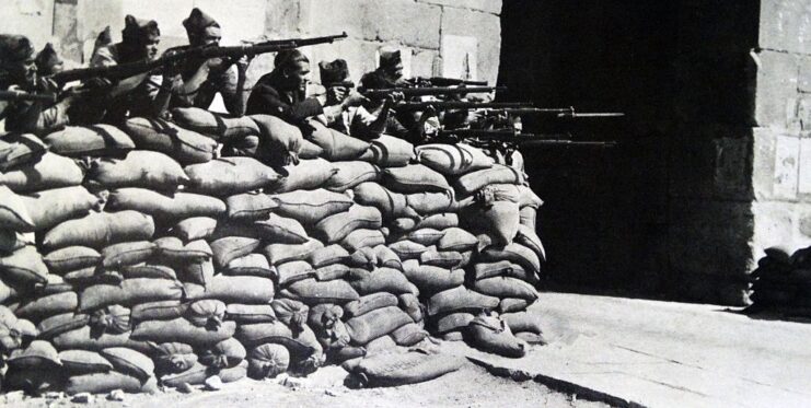 Nationalist soldiers aiming their rifles over a barricade made from sandbags