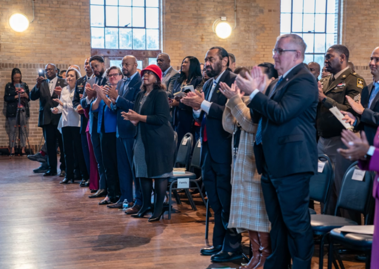 Individuals standing up and clapping in a large room