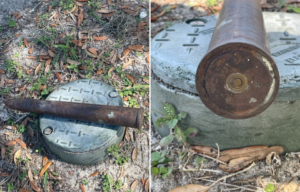 Live military round placed on a metal object outside + Close-up of the end of a live military round placed on a metal object outside