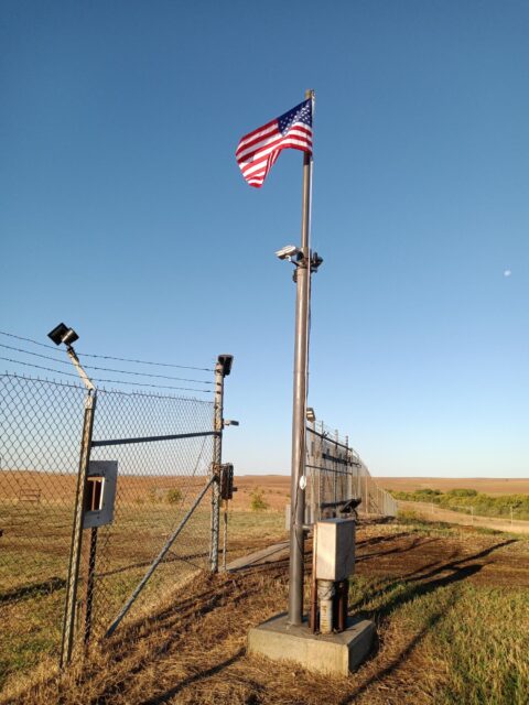 American flag flying in front of a metal gate