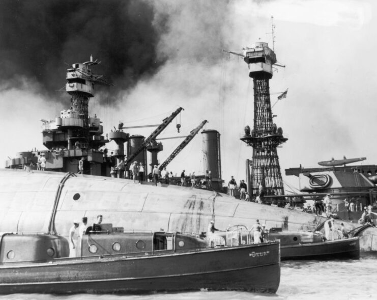 Rescue crews standing atop a capsized USS Oklahoma (BB-37)