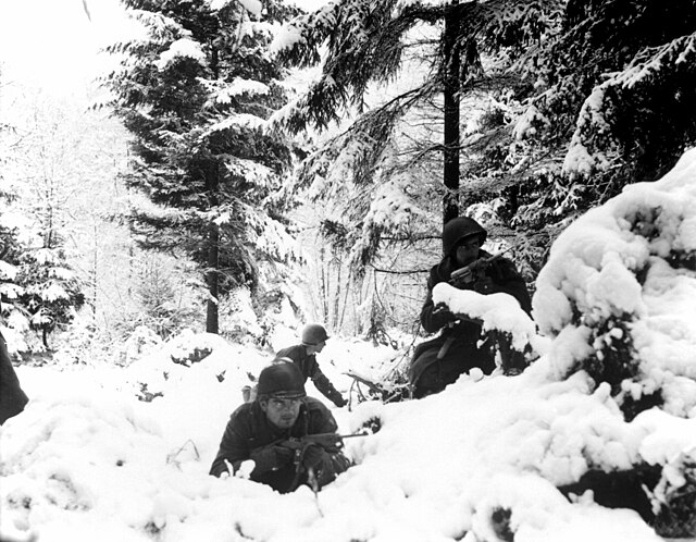 Three American infantrymen walking through the snow