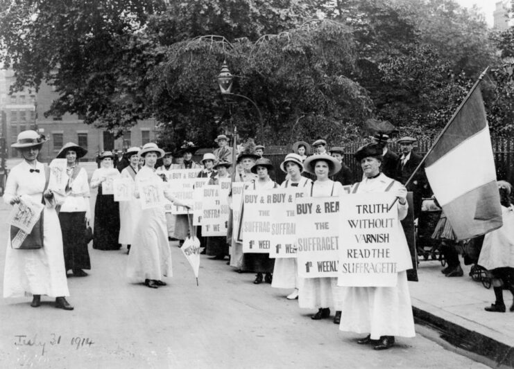 British Suffragettes holding signs while standing on a street