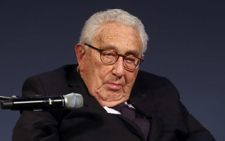 Henry Kissinger sitting in front of a microphone