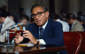 Henry Kissinger speaking at a microphone