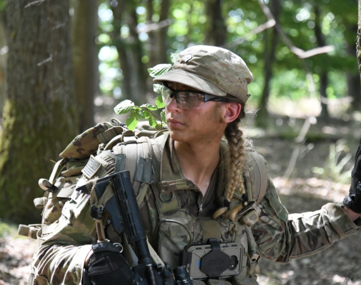 Maciel Hay walking in a wooded area in her US Army fatigues