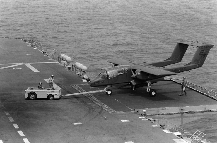 Vehicle pulling a North American Rockwell OV-10A Bronco on the flight deck of the USS Nassau (LHA-4)
