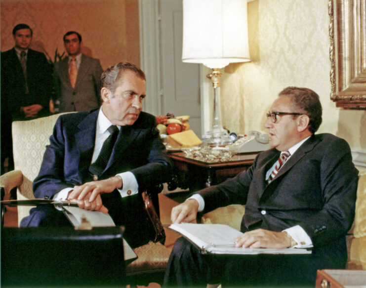 Richard Nixon and Henry Kissinger talking while sitting in chairs
