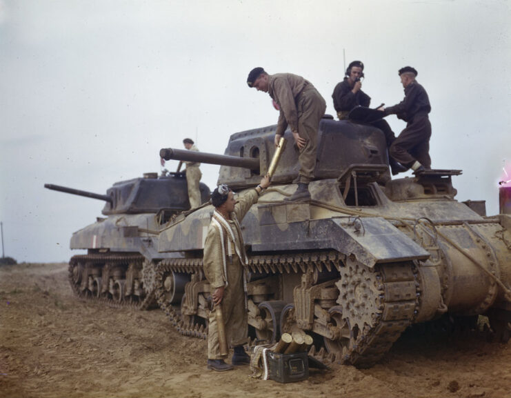 Soldiers sitting atop two Tank, Cruiser, Ram Mk IIs in a muddy field