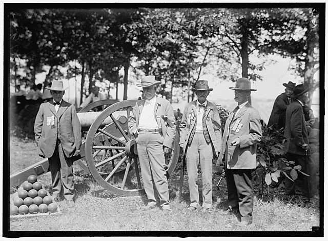 Four American Civil War veterans standing near a cannon