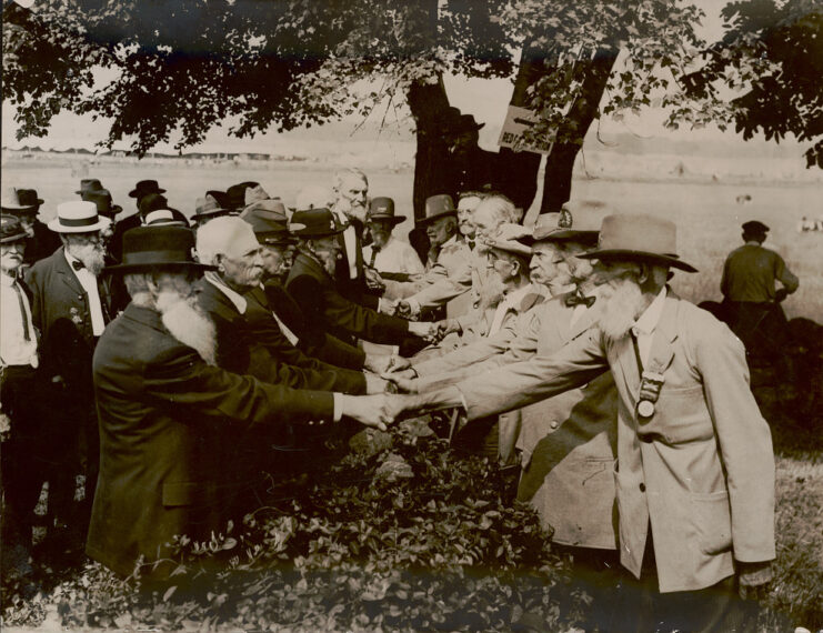 Confederate and Union soldiers shaking hands at the 1913 Gettysburg Reunion