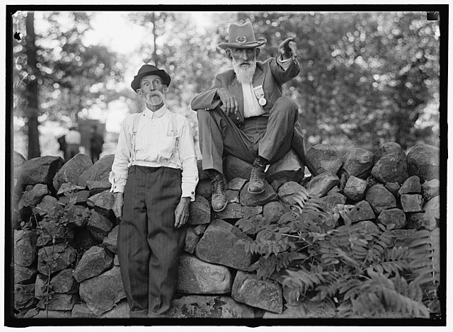 American Civil War veteran leaning against a stone wall while another sits atop it