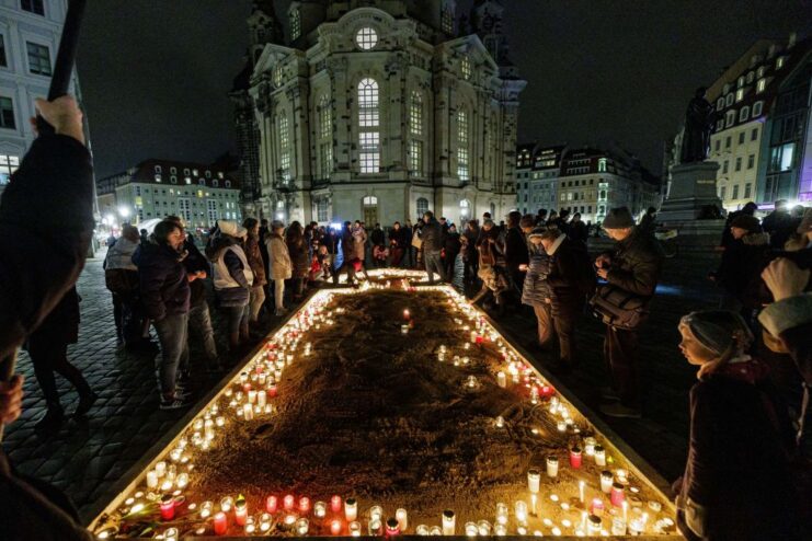 Crowd gathered around lit candles on the ground