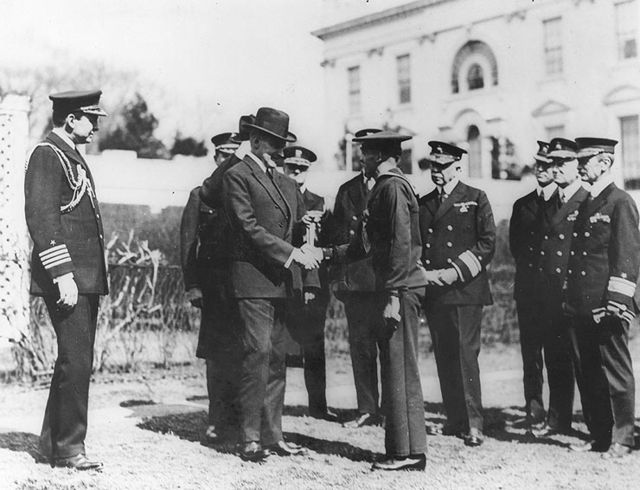 US Navy personnel watching as Calvin Coolidge shakes hands with Henry Breault