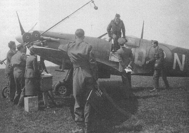 Johnnie Johnson climbing out of a Supermarine Spitfire while a media crew stands nearby