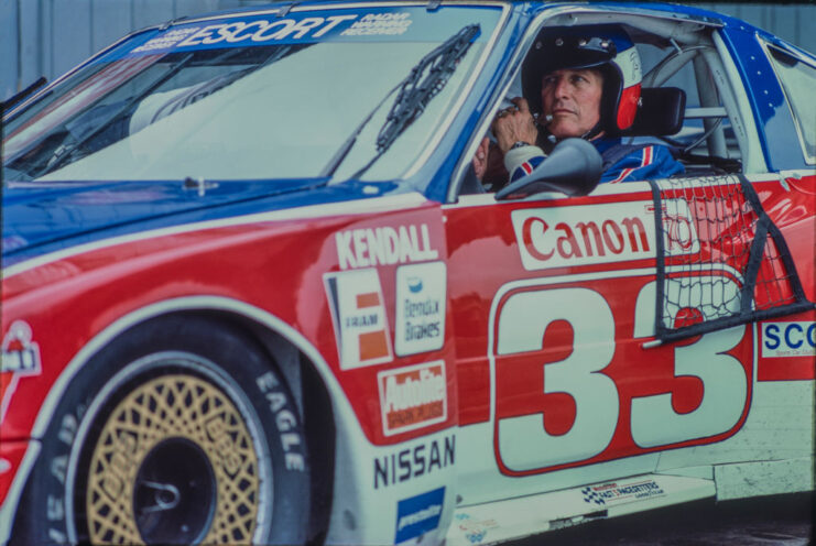 Paul Newman sitting in the driver's seat of a race car