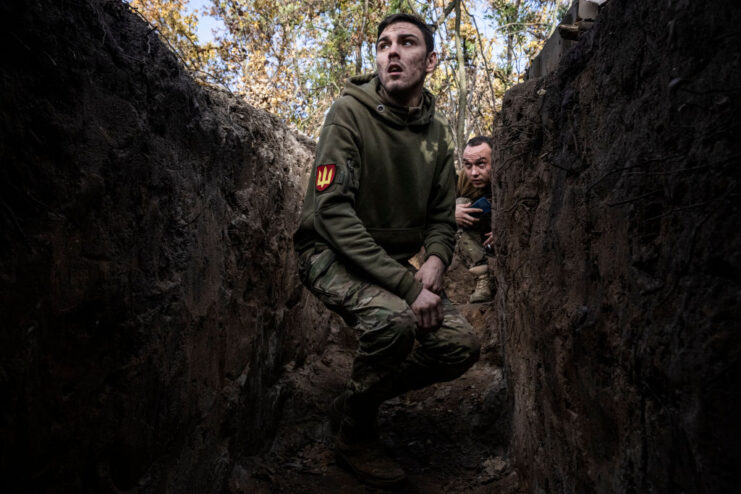 Two soldiers peering over the top of a trench